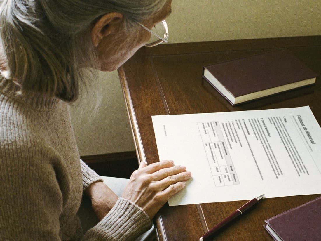 A reader at a table rereads the page translated into French, one hand resting on the sheet.